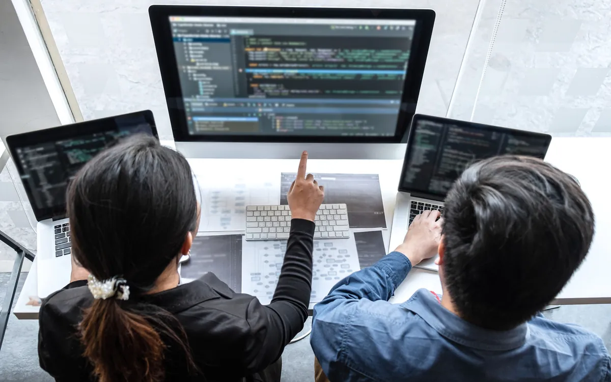 Developers writing code together, code open on the screens