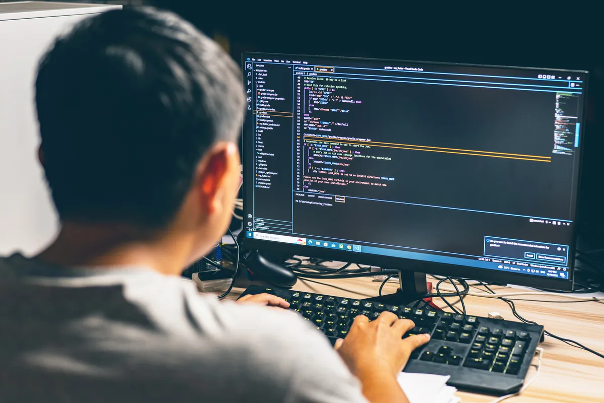 A developer working through code on a large monitor