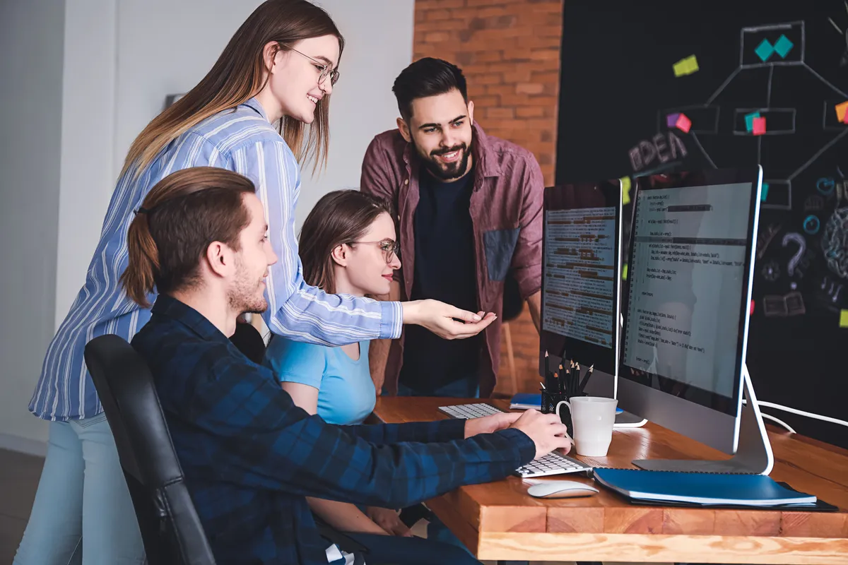 A team of programmers working together at one desk