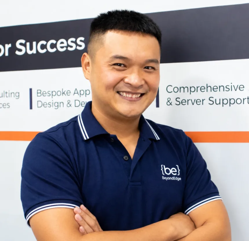 A BeyondEdge project manager, arms folded, in front of the company banner