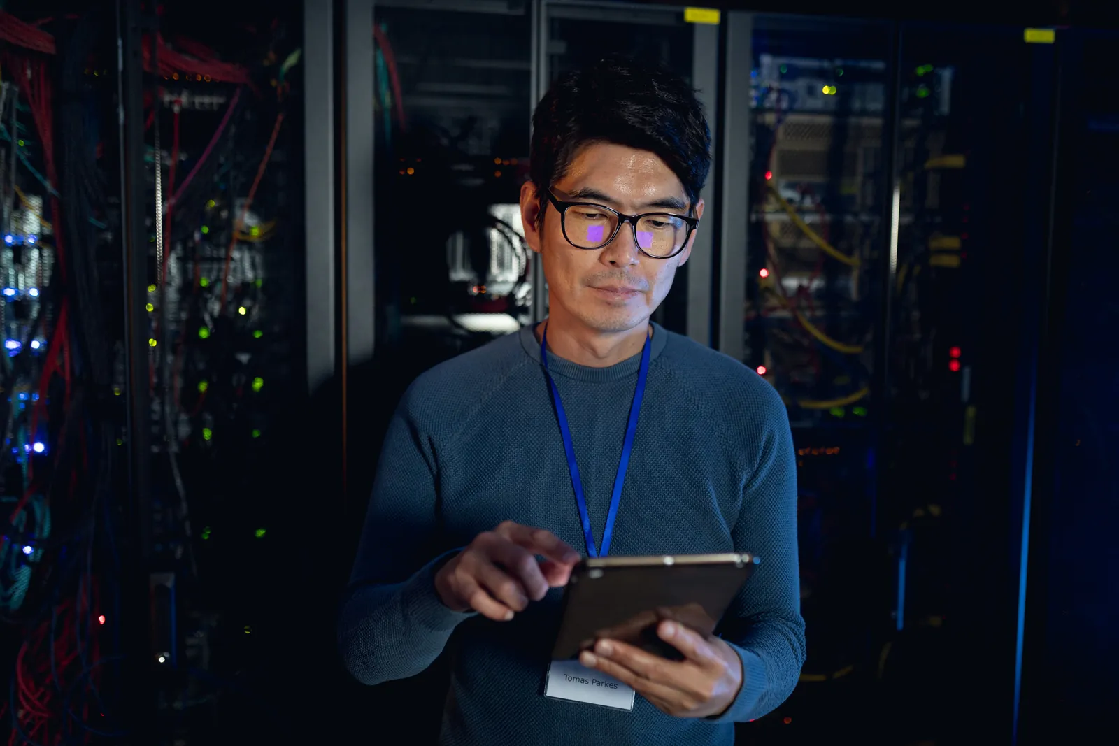 An engineer reviewing systems on a tablet in a modern server room